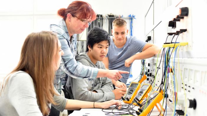 Eine Gruppe von jungen Menschen arbeitet gemeinsam an Elektronikprojekten in einem Ingenieurlabor.