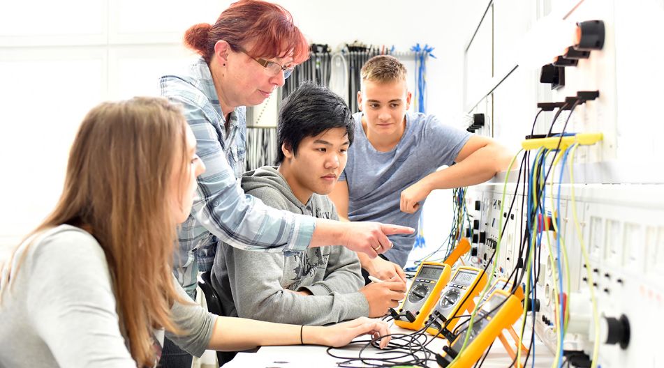 Eine Gruppe von jungen Menschen arbeitet gemeinsam an Elektronikprojekten in einem Ingenieurlabor.