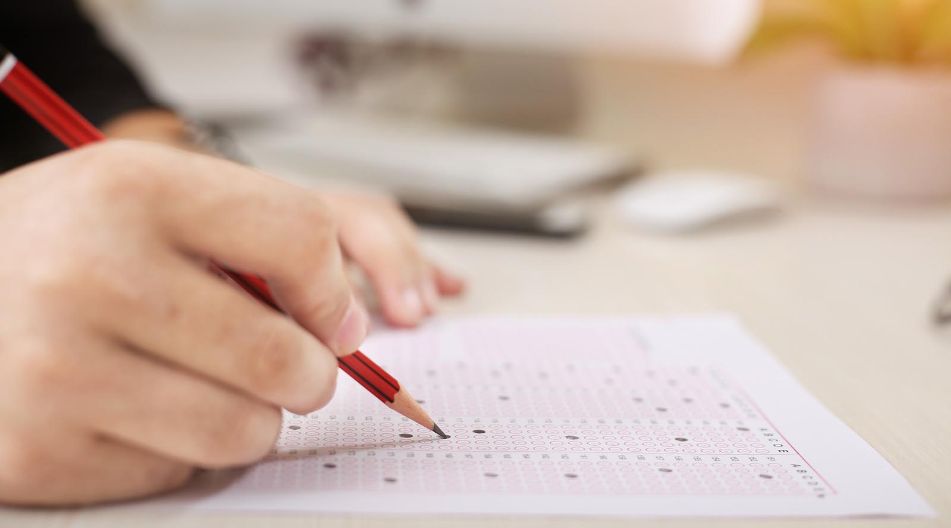 Eine Person schreibt mit einem Bleistift auf ein Stück Papier.