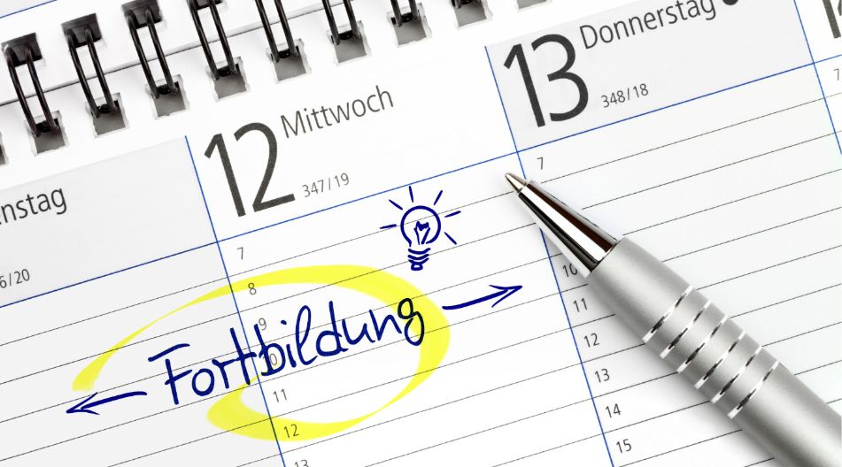 Ein Kalenderblatt mit den Daten Mittwoch, 12., und Donnerstag, 13.; der Eintrag "Fortbildung" ist handschriftlich eingetragen und gelb markiert, daneben ein gezeichneter Glühbirnen-Sketch. Ein silberner Kugelschreiber liegt auf dem Kalender.