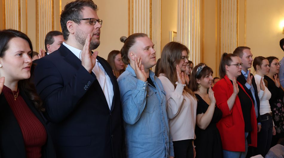 Mehrere angehende Referendare heben bei ihrem Dienstanritt die Hand zur Vereidigung.