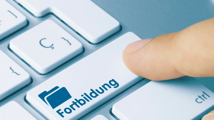 Finger drückt eine Taste auf der Tastatur mit der Aufschrift „Fortbildung“.