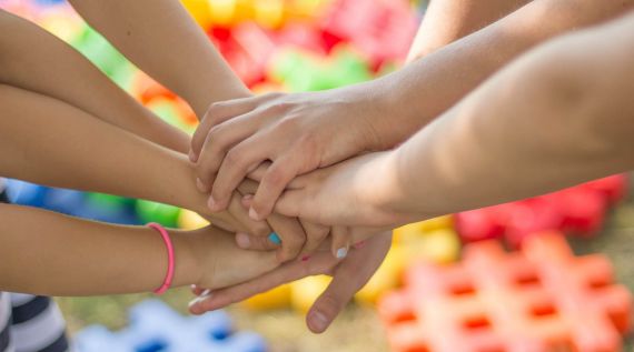 Eine Gruppe von Kinderhänden, die sich gegenseitig halten, zeigt Gemeinschaft und Unterstützung.