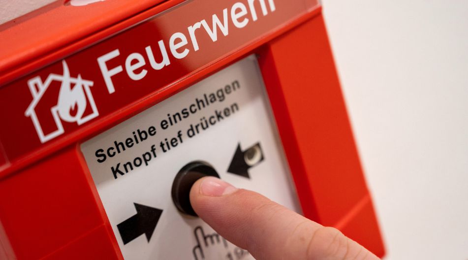 Ein Finger betätigt den Notknopf zum Rufen der Feuerwehr.