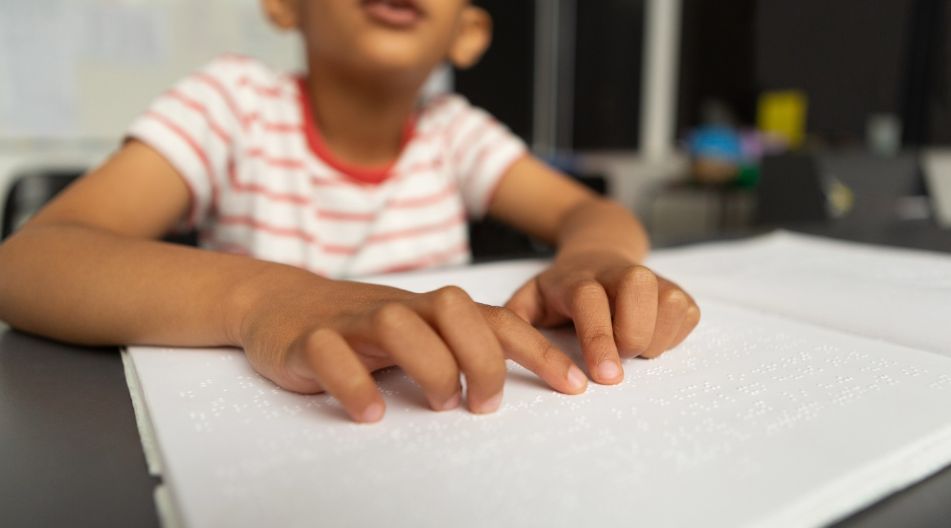 Kinderhände lesen ein Blatt mit Blindenschrift