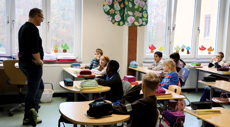 Eine multikulturelle Klasse der Grundschule Campus am Turm aus Schwerin hört im Klassenraum einer Lehrkraft zu.