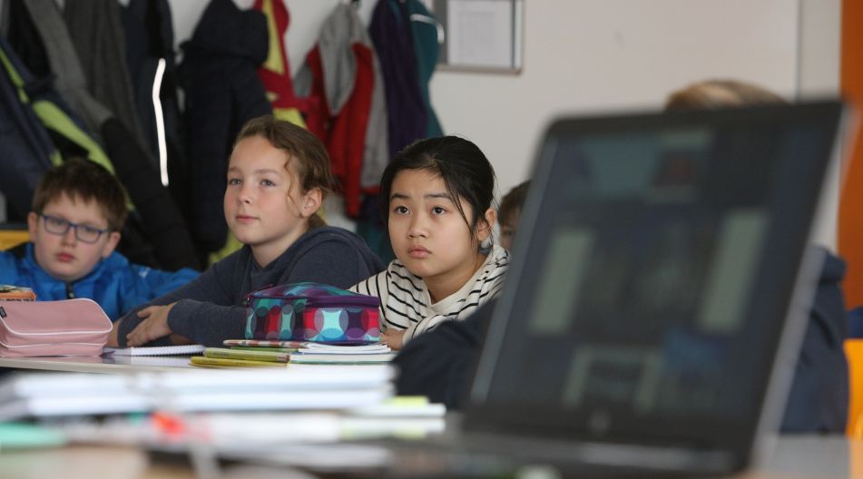 Schülerinnen und Schüler schauen interessiert im Unterricht nach vorn.