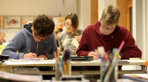 Zwei Jungen sitzen am Schultisch und schreiben.