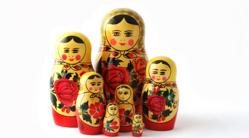 Eine Gruppe russischer Matroschka-Puppen in Rot- und Goldtönen, die traditionelles Handwerk repräsentieren.